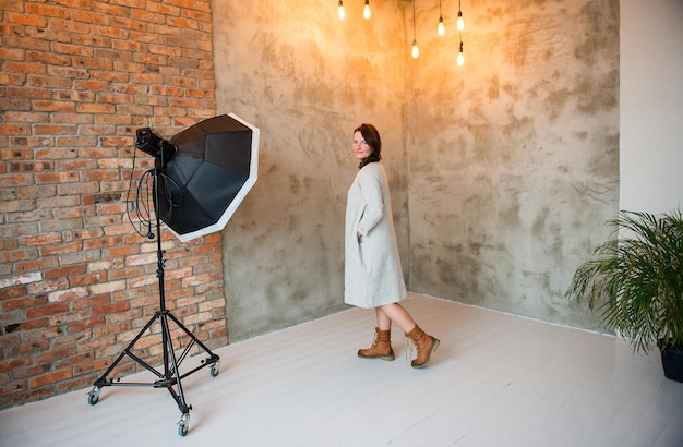 Foto ritratto di una giovane donna in piedi accanto al muro dello studio