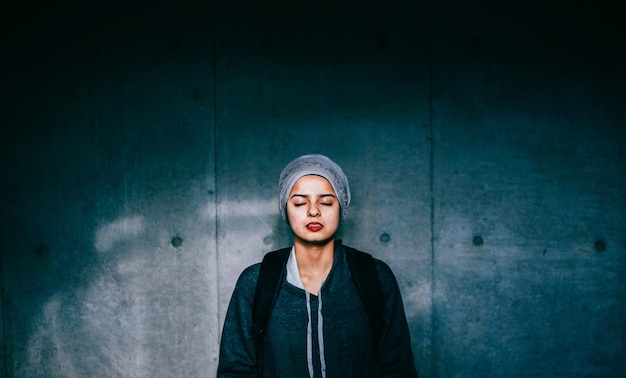 portrait of young woman standing by wall