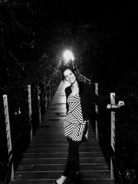 Photo portrait of young woman standing on footbridge at night