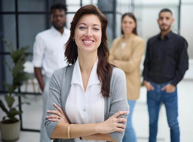 Portrait of a young woman standing in an office with colleagues in the background