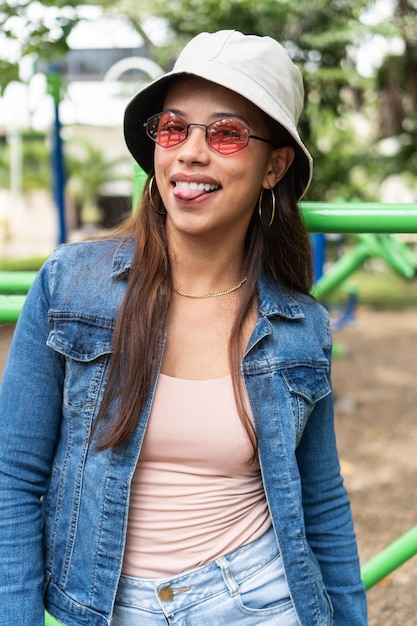 Portrait of a young woman standing outdoors and looking at the camera through sunglasses