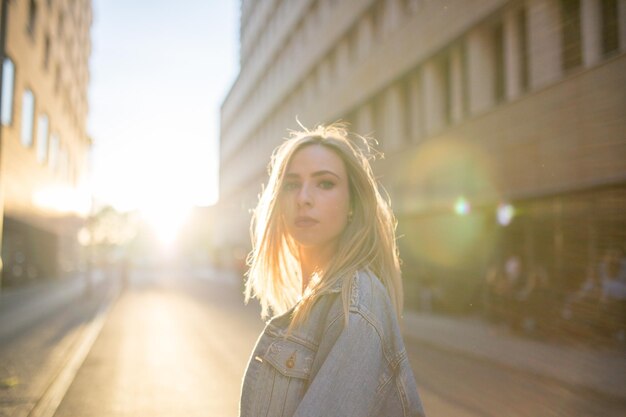 Portrait of young woman standing on road in city