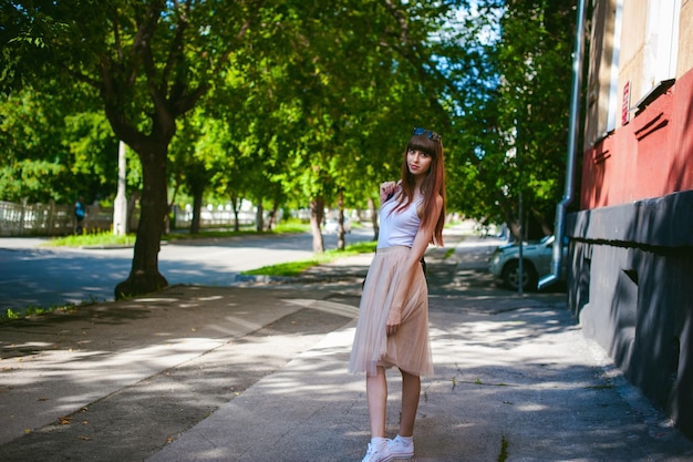 樹木に背を向けて歩道に立っている若い女性の肖像画