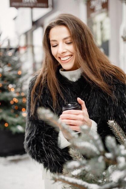 Portrait of young woman standing in winter town and posing for a photo