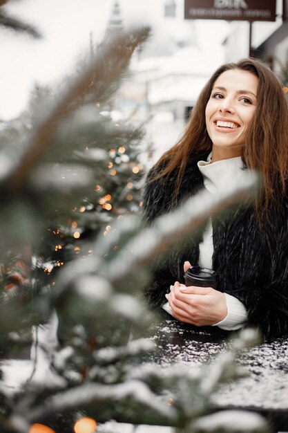 Portrait of young woman standing in winter town and posing for a photo