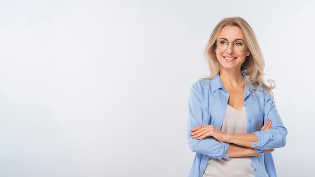 portrait of young woman standing with her crossed arms against white background