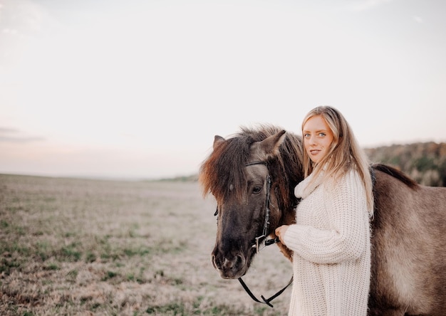 Portrait of young woman standing with horse on field against sky