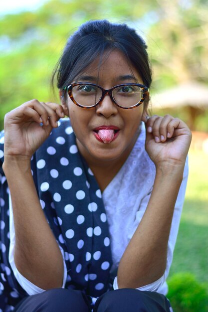 Portrait of young woman sticking out tongue in park