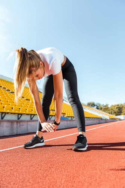 Portrait of a young woman stretching at stadium