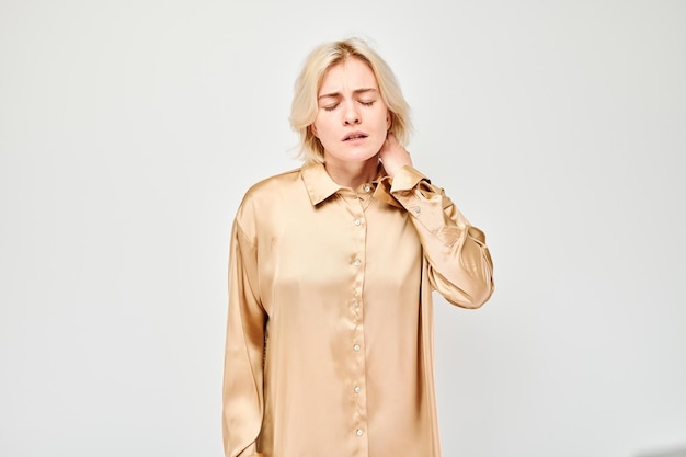 Portrait of young woman suffering from pain touching neck isolated on white studio background Psychosomatics of stress degenerative disease of spine