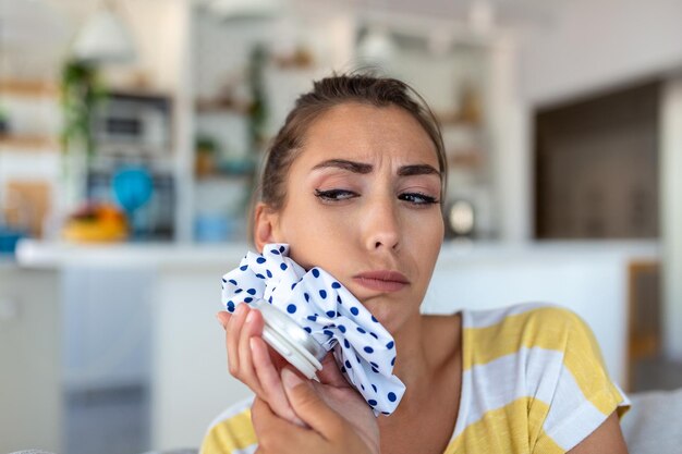 Portrait of young woman suffering from toothache cooling her face with a ice pack