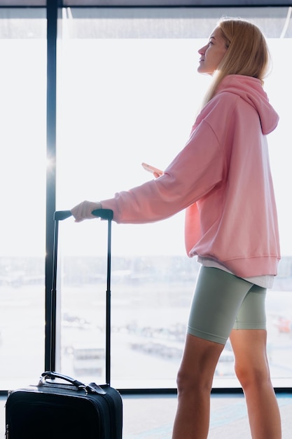 Portrait of a young woman in a suitcase and a mobile phone on
the background of the airport