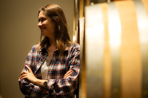 Portrait of a young woman surrounded by wine barrels In her winery