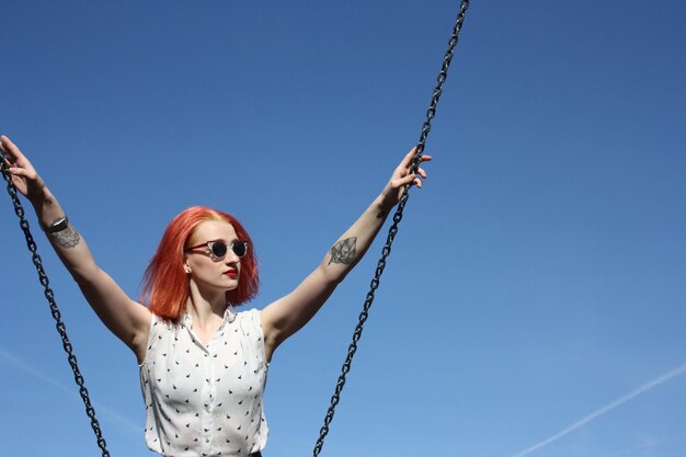 Photo portrait of young woman on swing against sky