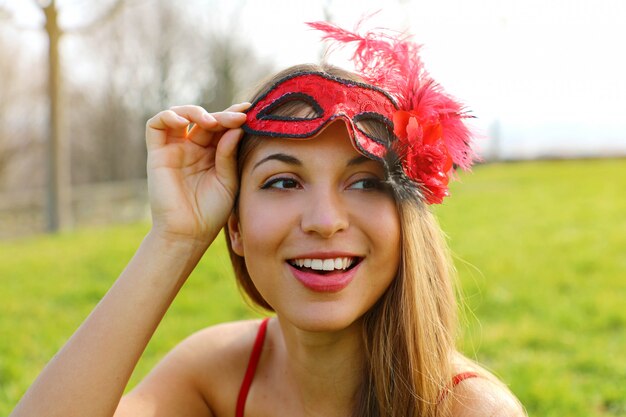 Portrait of a young woman taking off her Carnival mask