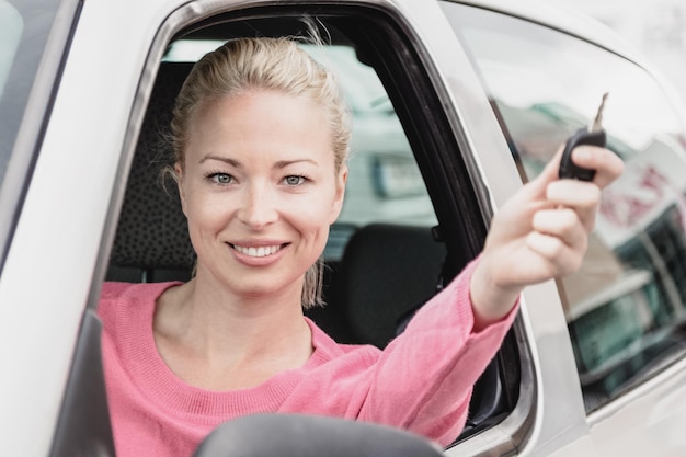 Photo portrait of young woman taking selfie while sitting in car