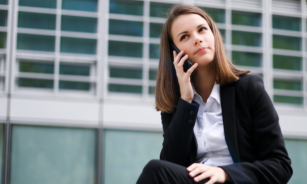 Ritratto di una giovane donna che parla al telefono seduto su una panchina all'aperto