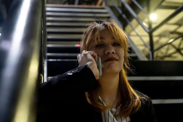 Photo portrait of young woman talking over smart phone on steps