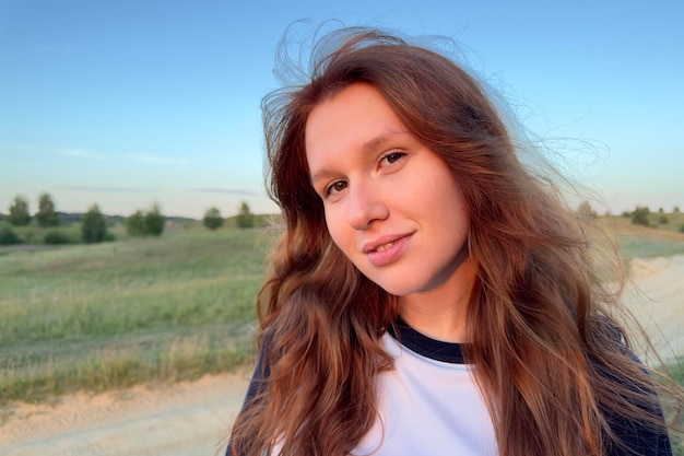 Portrait of young woman teenager girl having fun outdoors at countryside looking at camera and smile