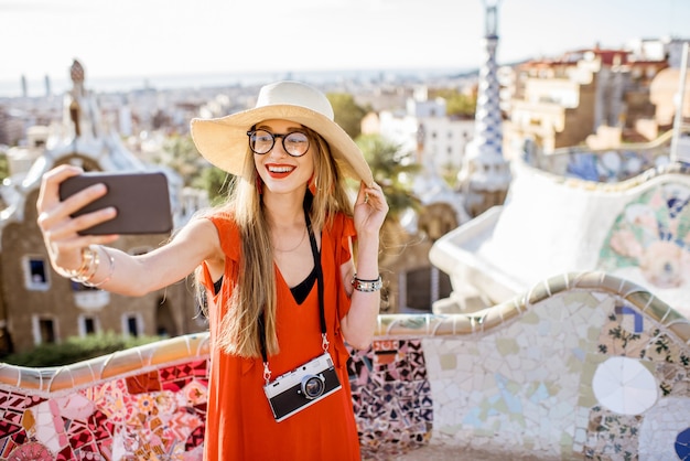 Portrait of a young woman tourist in red dress having fun visiting famous Guell park in Barcelona