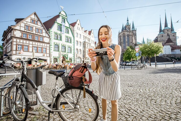 Portrait of a young woman tourist traveling with bicycle and photo camera in the old town of Erfurt city, Germany