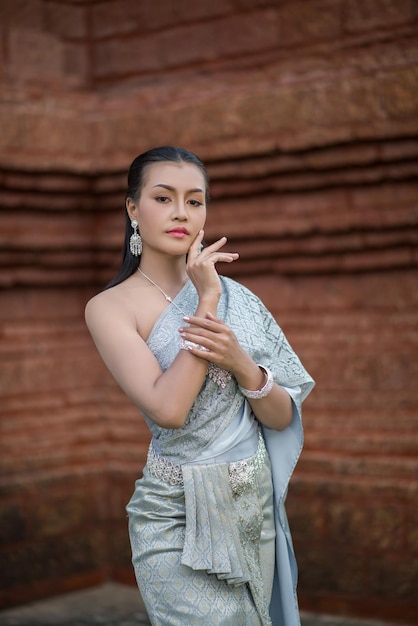 Portrait of young woman in traditional clothing standing against wall