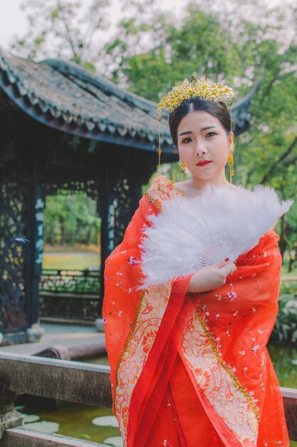 Photo portrait of young woman in traditional clothing standing at shrine