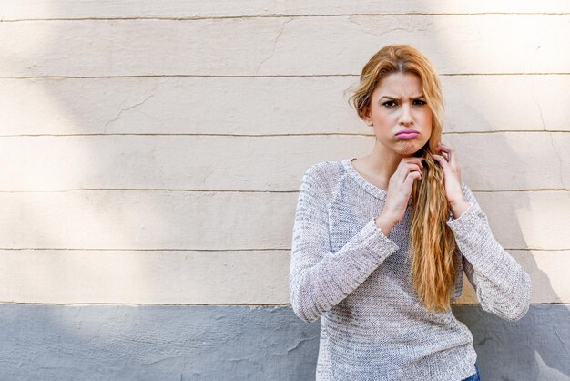 Portrait of young woman tying hair against wall