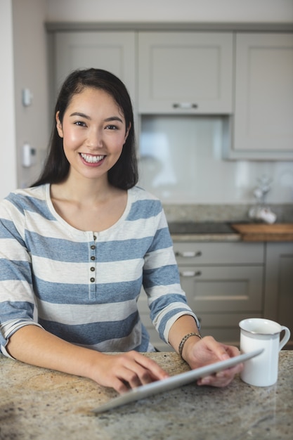 Portrait of young woman using a digital tablet in kitchen