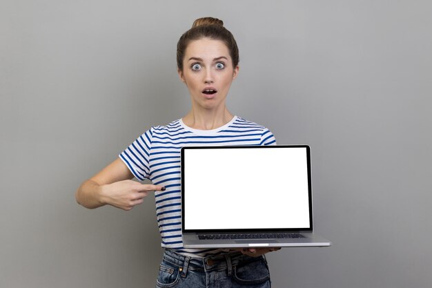 Photo portrait of young woman using digital tablet while standing against white background