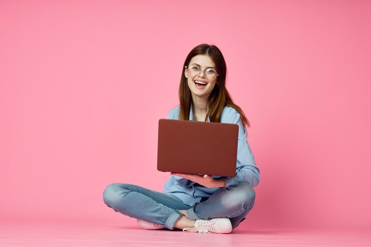 Photo portrait of young woman using laptop while sitting against yellow background