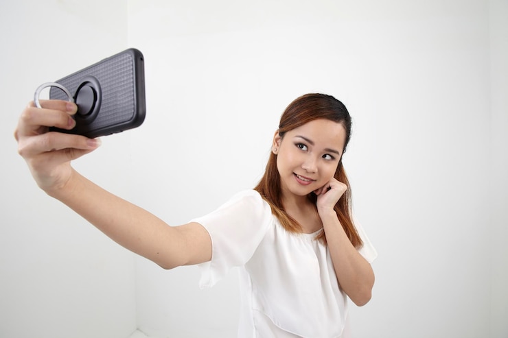 Photo 白い壁に携帯電話を使っている若い女性の肖像画