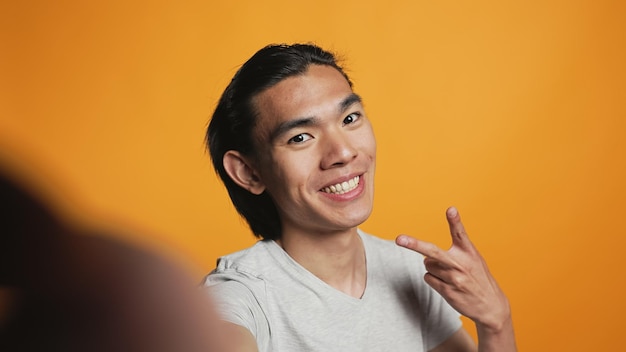 Portrait of young woman using mobile phone against yellow background