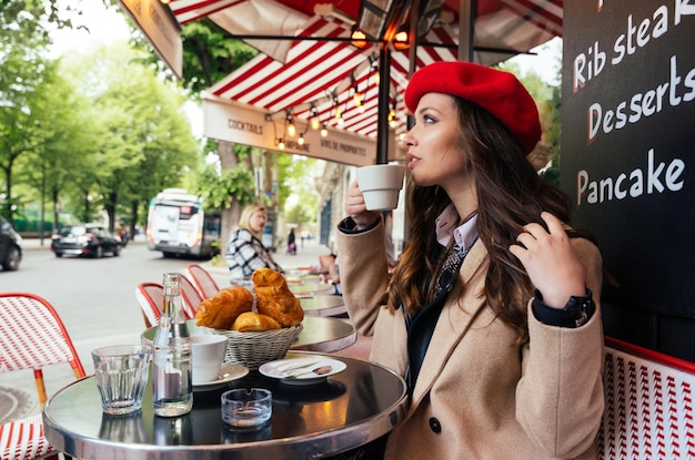 Foto ritratto di una giovane donna che usa il telefono cellulare in un caffè