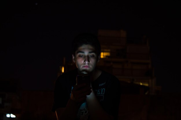 Photo portrait of young woman using mobile phone at night