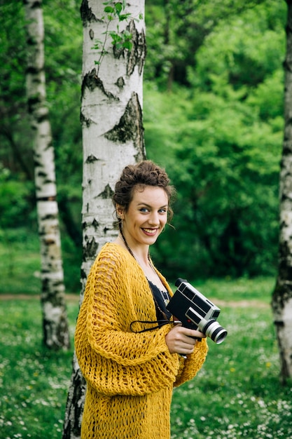 Portrait of young woman using a vintage cinema camera in a park