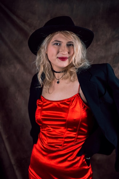 Портрет молодой женщины в красном платье и шляпе, изолированный на темном фоне
