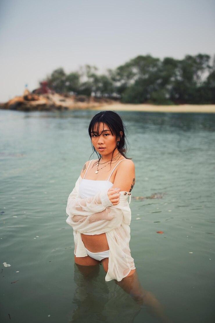Photo  ⁇ 은 하늘 아래 바다에 서 있는 비키니를 입은 젊은 여성의 초상화