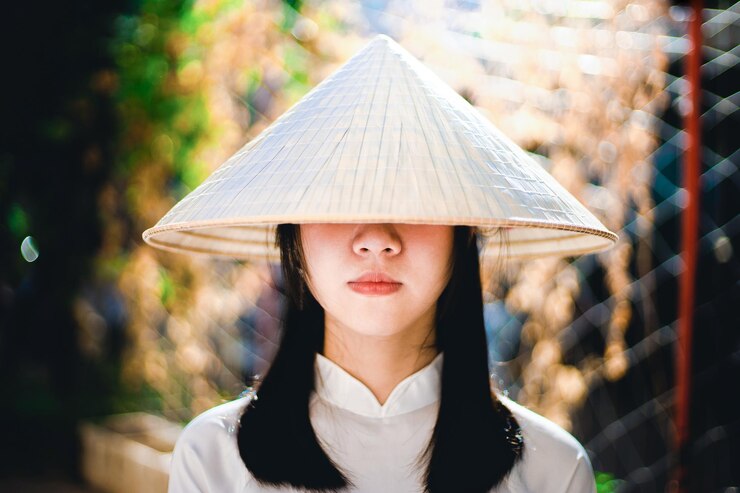 Photo 흐릿한 배경에 서 있는 피침 모자를 입은 젊은 여성의 초상화