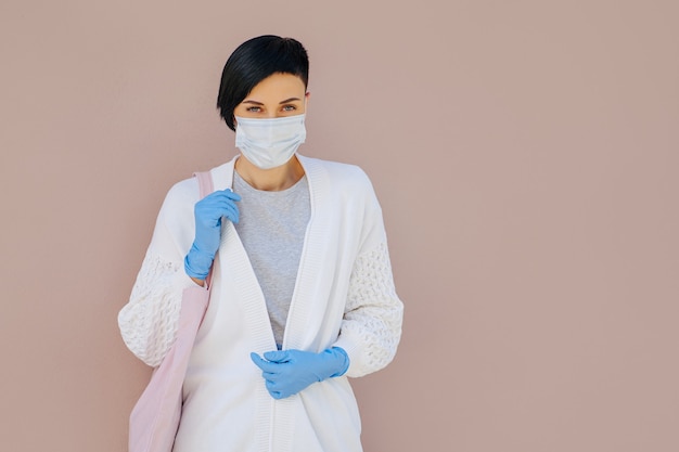 Portrait young woman wearing cotton mask and medical gloves with shopping bag on the street during Covid 19 outbreak. Protection in prevention for coronavirus.