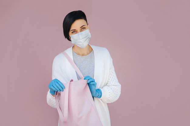 Portrait young woman wearing cotton mask and medical gloves with shopping bag on the street during Covid 19 outbreak. Protection in prevention for coronavirus.