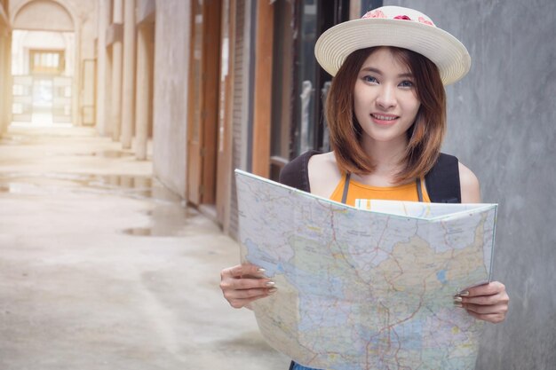 Foto ritratto di una giovane donna che indossa un cappello con una mappa in piedi nel corridoio