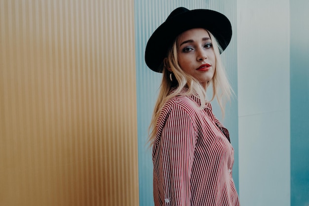 Photo portrait of young woman wearing hat while standing against wall