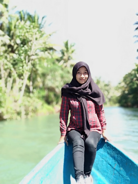 Portrait of young woman wearing hijab sitting on boat in lake during sunny day