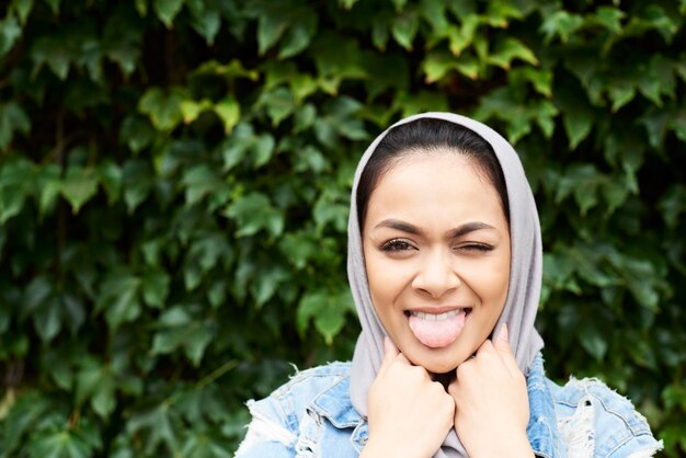 Портрет молодой женщины в хиджабе, высовывающей язык