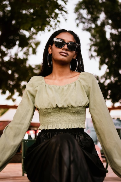 Photo portrait of a young woman wearing light green blouse black skirt and sunglasses and hoop earrings