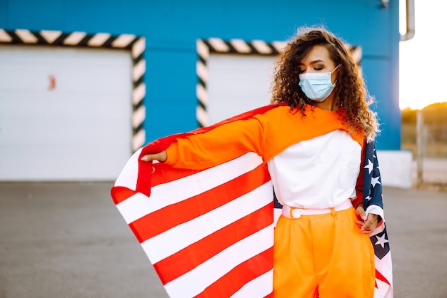 Portrait of a young woman wearing mask and holding flag