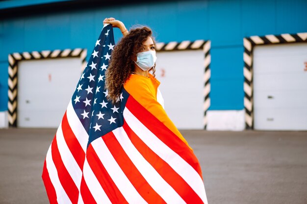 Portrait of a young woman wearing mask and holding flag