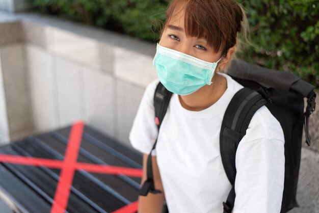 Photo portrait of young woman wearing mask sitting outdoors