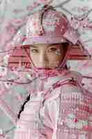 Photo portrait of a young woman wearing a pink samurai helmet and armor